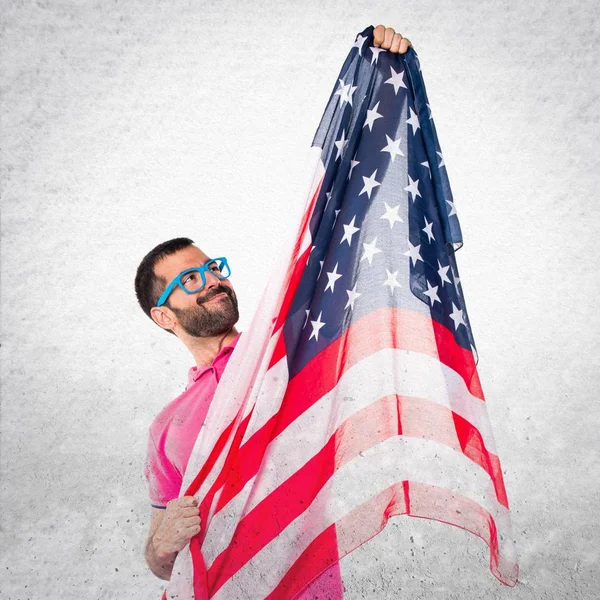 灰色 textu にアメリカの国旗を保持しているカラフルな服を持つ男 — ストック写真