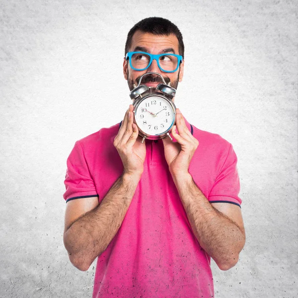 Homme avec des vêtements colorés tenant horloge vintage sur gris texturé — Photo