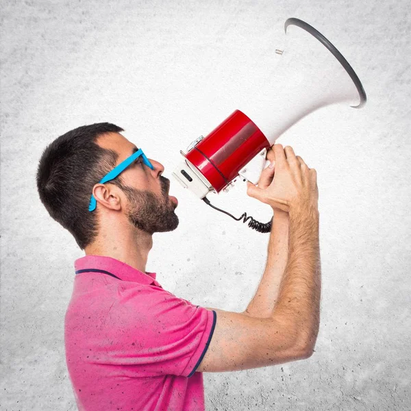 Мужчина в красочной одежде, кричащий мегафоном на серой текстуре — стоковое фото