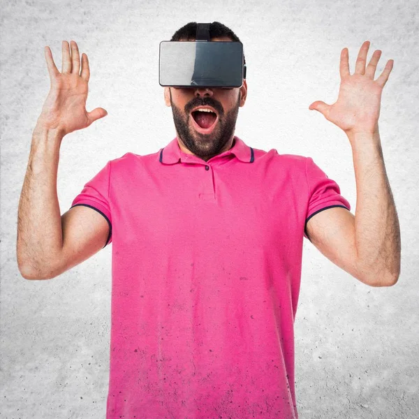 Homem com roupas coloridas usando óculos VR em cinza texturizado de volta — Fotografia de Stock