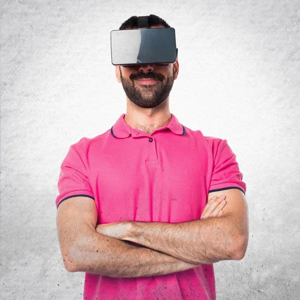 Man with colorful clothes using VR glasses on grey textured back — Stock Photo, Image