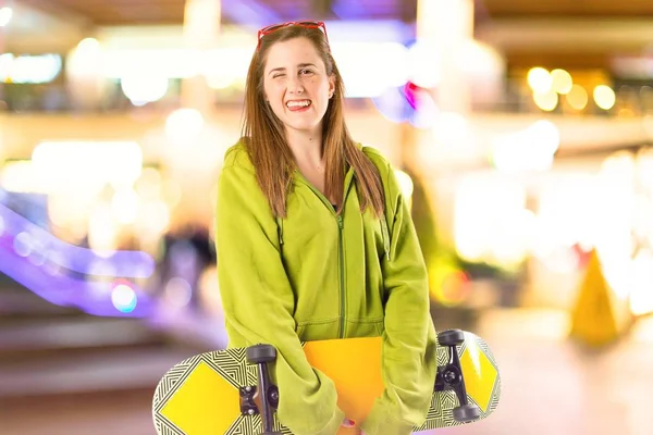 Ragazza bionda con skate su sfondo bianco — Foto Stock