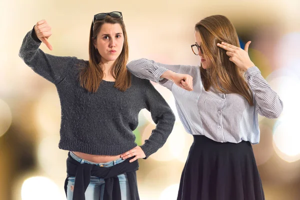 Twin sisters making suicide gesture and bad sign — Stock Photo, Image