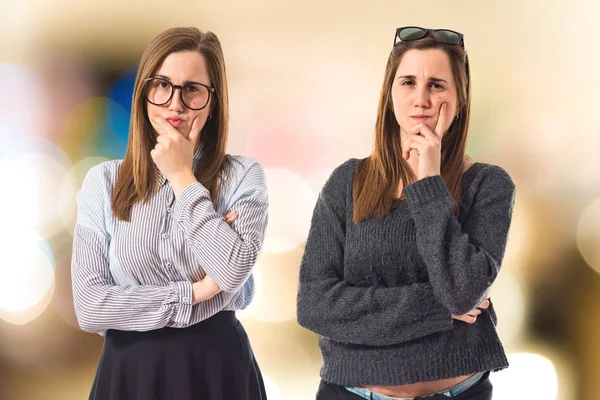 Hermanas gemelas pensando sobre fondo blanco —  Fotos de Stock