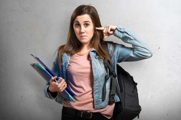 Adolescente estudiante chica sosteniendo libros y cubriendo sus oídos — Foto de Stock