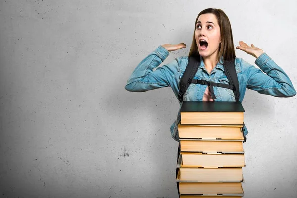 Tiener student meisje met een heleboel boeken verrassing gebaar maken — Stockfoto