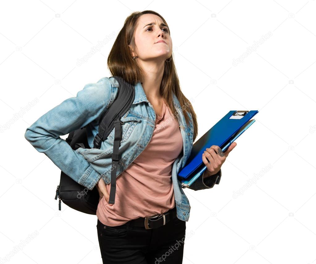 Teen student girl holding books and with back pain