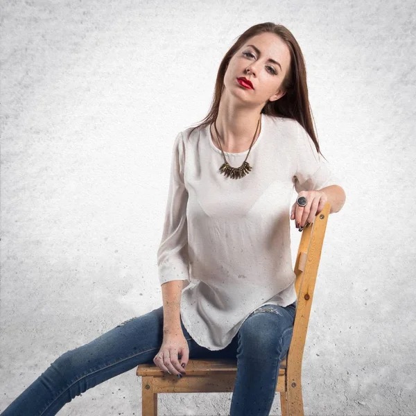 Joven modelo bonita mujer posando en estudio en silla en g texturizado — Foto de Stock