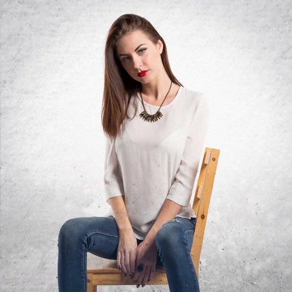 Young pretty model woman posing in studio on chair on textured g — Stock Photo, Image