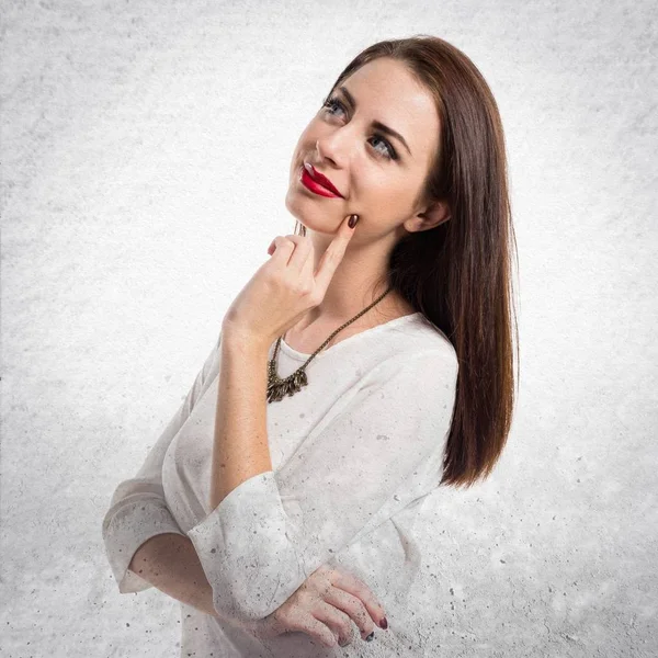 Pretty genç kız dokulu gri arka plan üzerinde düşünme