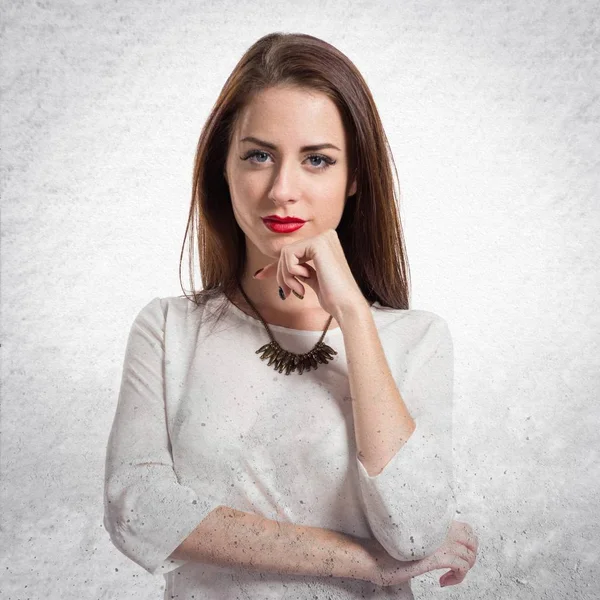 Pretty genç kız dokulu gri arka plan üzerinde düşünme