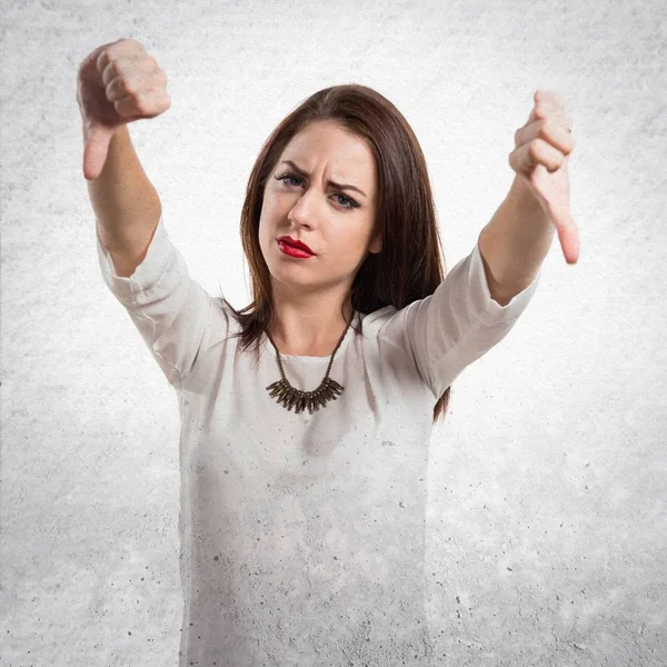 Pretty young girl making bad signal on textured grey background — Stock Photo, Image