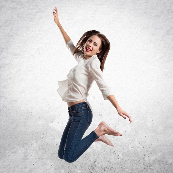 Pretty young girl jumping on textured grey background — Stock Photo, Image