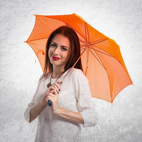 Mooie jonge meisje een paraplu getextureerde grijs pagina vasthouden — Stockfoto