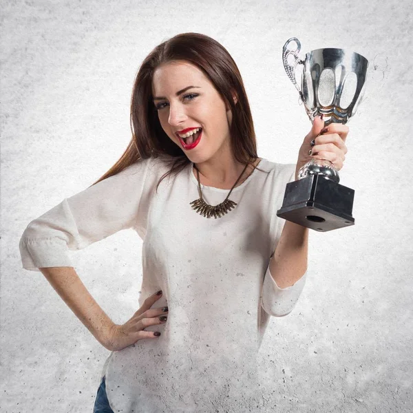 Bella ragazza in possesso di un trofeo su sfondo grigio strutturato — Foto Stock