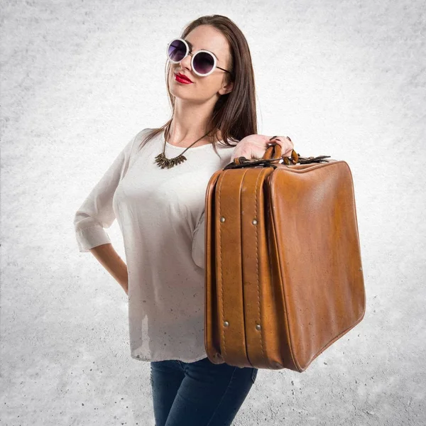 Bella ragazza con gli occhiali da sole in possesso di una valigetta vintage su — Foto Stock