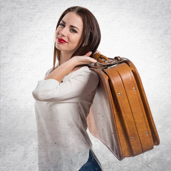 Chica bastante joven sosteniendo un maletín vintage en gris texturizado b — Foto de Stock