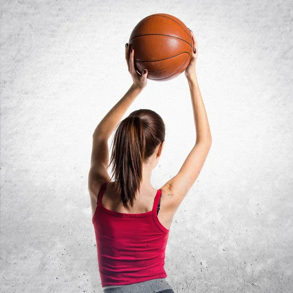 Pretty sport woman playing basketball on textured grey backgroun