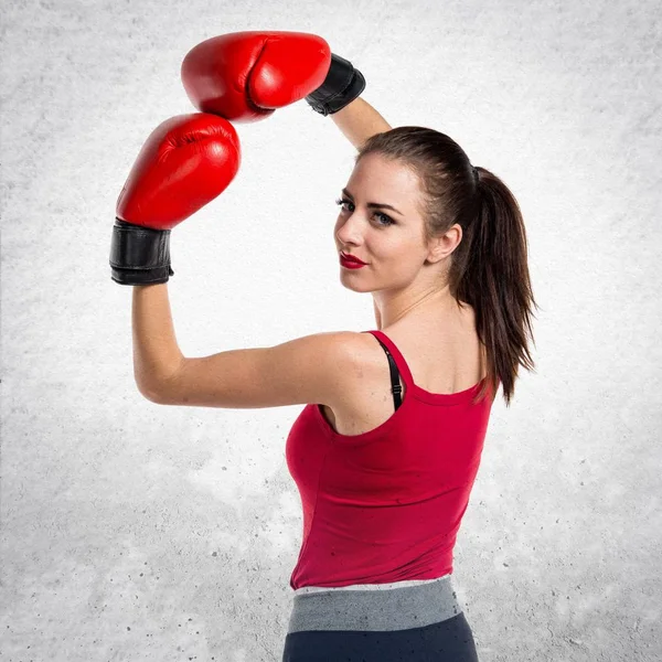 Mujer bastante deportiva con guantes de boxeo sobre fondo gris texturizado —  Fotos de Stock