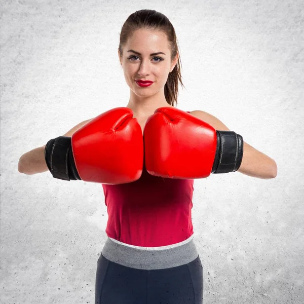 Mujer bastante deportiva con guantes de boxeo sobre fondo gris texturizado —  Fotos de Stock