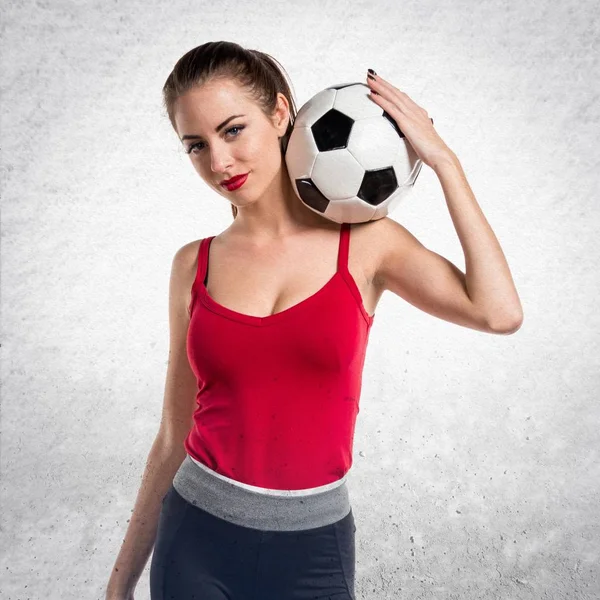 Bella donna sportiva che tiene un pallone da calcio su schienale grigio strutturato — Foto Stock