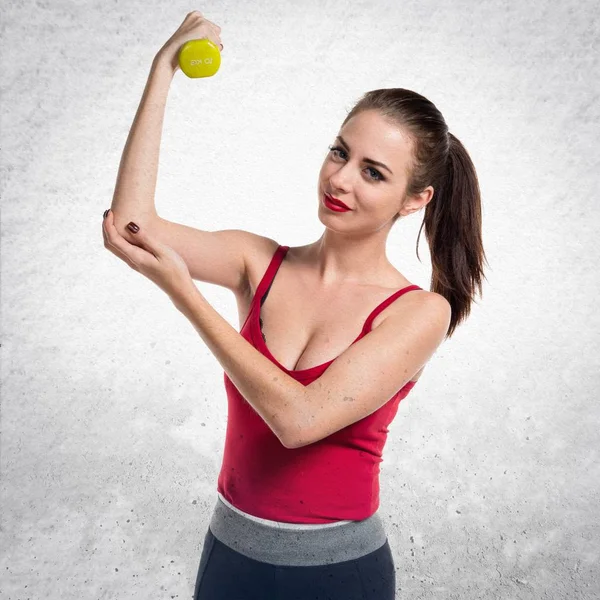 Красивая спортивная женщина делает тяжёлую атлетику на серой текстуре бэкгро — стоковое фото
