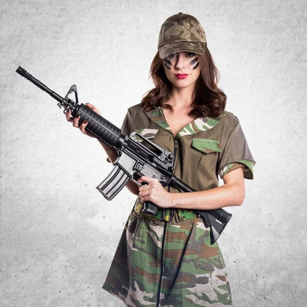 Militära kvinna som håller ett gevär på texturerat grå bakgrund — Stockfoto