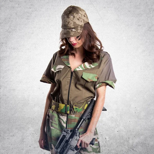 Military woman holding a rifle on textured grey background
