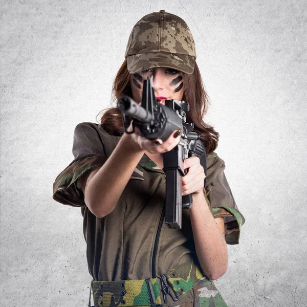 Military woman holding a rifle on textured grey background