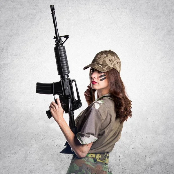 Militära kvinna som håller ett gevär på texturerat grå bakgrund — Stockfoto