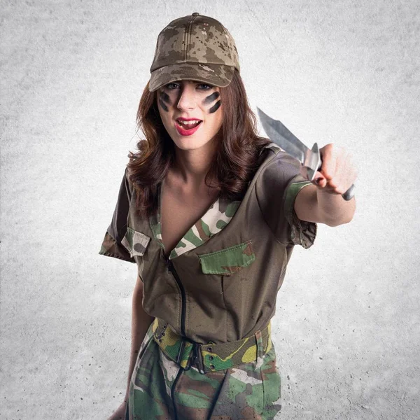 Militära flicka håller en kniv på texturerat grå bakgrund — Stockfoto