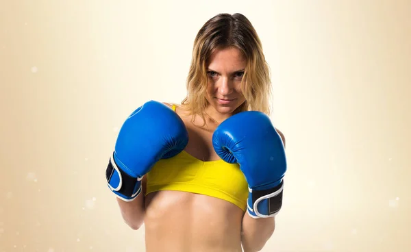 Koyu sarı zemin üzerine mavi boks eldivenli güzel sarışın kadın — Stok fotoğraf