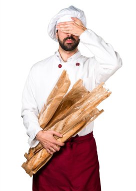 Biraz ekmek tutarak ve gözlerini kapsayan genç baker