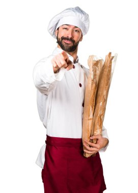 Biraz ekmek tutarak ve öne doğru işaret eden genç baker