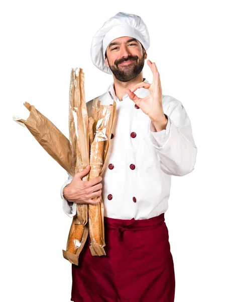 Молодой пекарь держит хлеб и делает знак ОК — стоковое фото