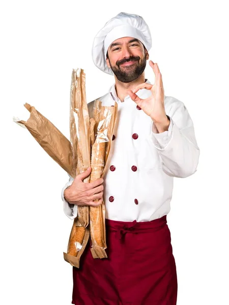 Jovem padeiro segurando um pouco de pão e fazendo OK sinal — Fotografia de Stock