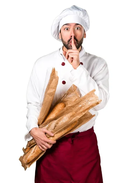 Joven panadero sosteniendo un poco de pan y haciendo un gesto de silencio —  Fotos de Stock