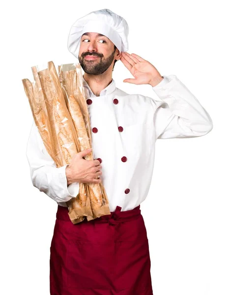 Young baker holding some bread and listening something — Stock Photo, Image
