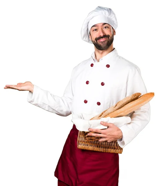 Młody piekarz trzyma chleb i prezentując coś — Zdjęcie stockowe