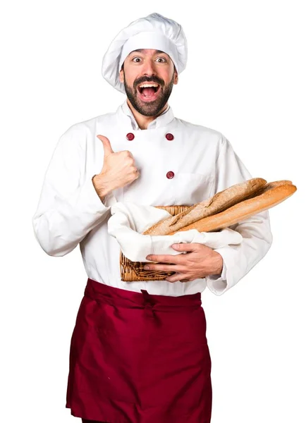 Fiatal baker gazdaság kenyeret és a hüvelykujjával felfelé — Stock Fotó