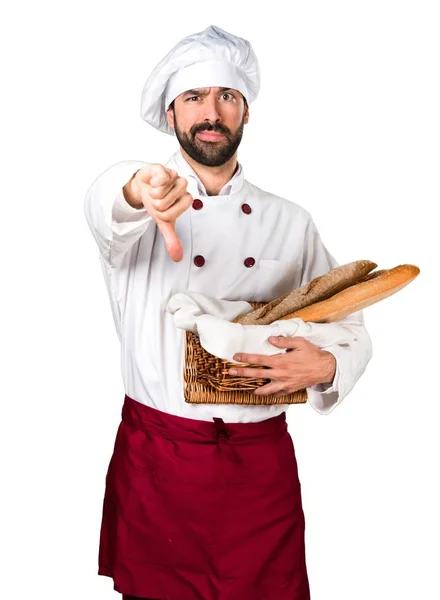 Young baker holding some bread and making bad signal — Stock Photo, Image