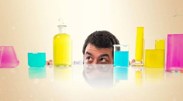 Scientist hiding behind test tubes on ocher background — Stock Photo, Image