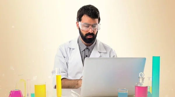 Científico hombre que trabaja con su ordenador portátil en el fondo ocre — Foto de Stock