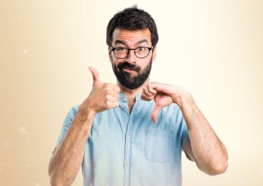 Yakışıklı adam iyi-kötü işareti üzerinde koyu sarı arka plan yapma