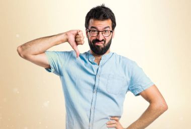 Yakışıklı adam mavi gözlük okra backgro üzerinde kötü sinyal yapıyor