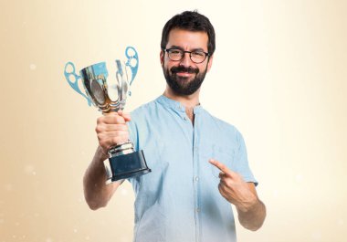 Bir kupa üzerinde koyu sarı backgro tutan mavi gözlüklü yakışıklı adam