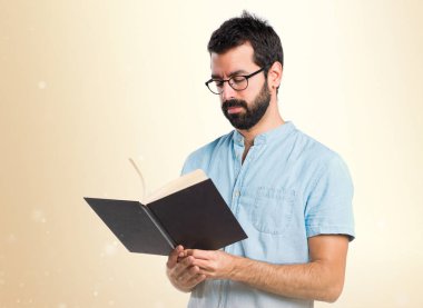 Mavi gözlük koyu sarı zemin üzerine kitap okuma ile yakışıklı adam