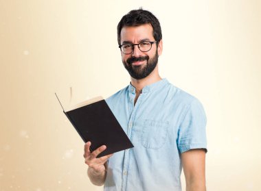 Mavi gözlük koyu sarı zemin üzerine kitap okuma ile yakışıklı adam