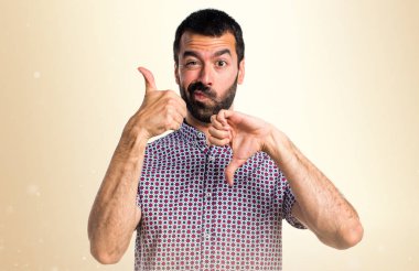 Yakışıklı adam iyi-kötü işareti üzerinde koyu sarı arka plan yapma