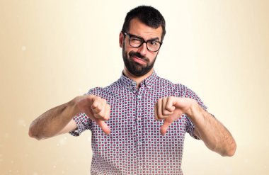 Koyu sarı zemin üzerine kötü sinyal yapıyor gözlüklü adam